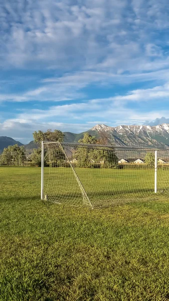 Vertical White soccer goal on a grassy sports field with view of snow topped mountain — Stock Photo, Image