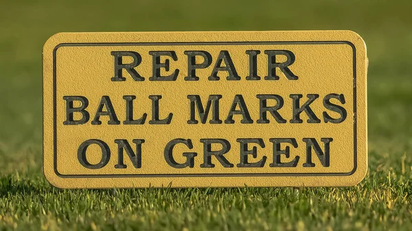 Panorama ram närbild av en skylt vid en golfbana Läs reparation boll märken på grön — Stockfoto
