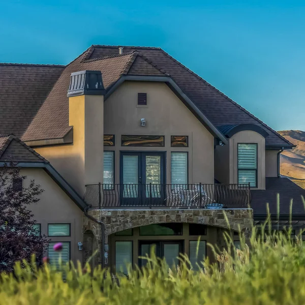 Plaza Hermosa casa con balcón vista detrás de hierbas verdes vibrantes en un día soleado — Foto de Stock