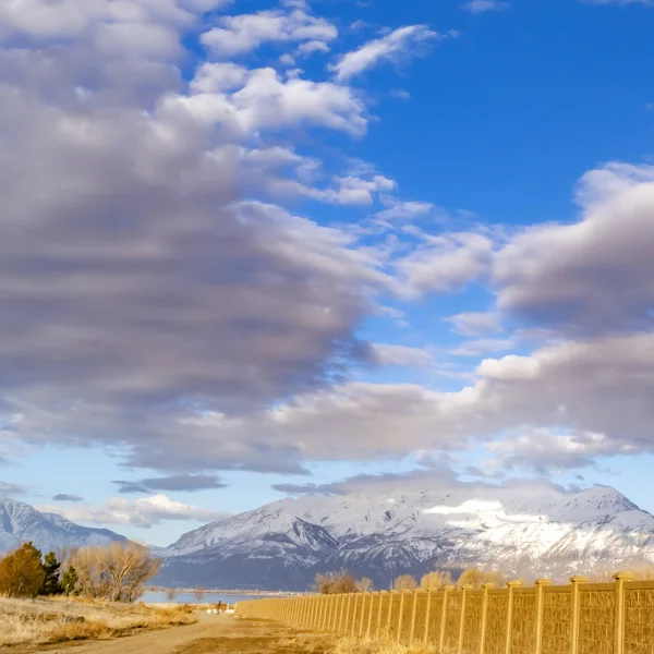 Piazza Vibrante cielo blu con nuvole gonfie su un lago e grande neve ricoperta montagna — Foto Stock