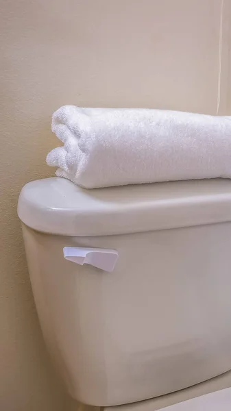 Marco vertical Cierre del inodoro de un baño con una toalla doblada en la parte superior del tanque —  Fotos de Stock