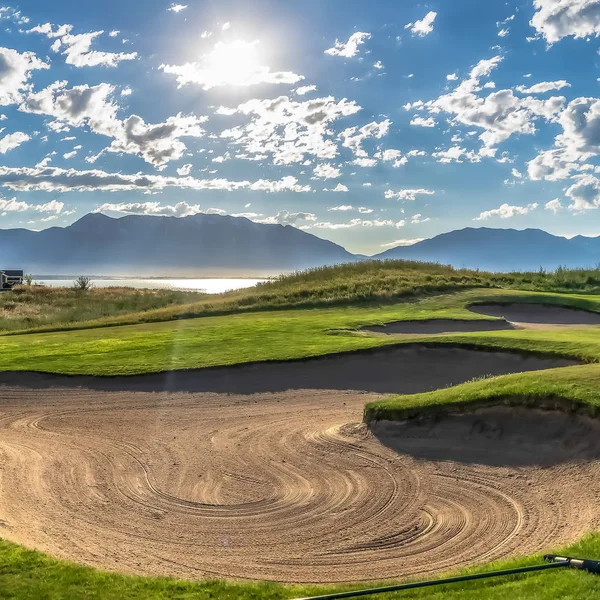 Quadratischer Sandbunker eines Golfplatzes und Blick auf strahlende Sonne und geschwollene Wolken am Himmel — Stockfoto