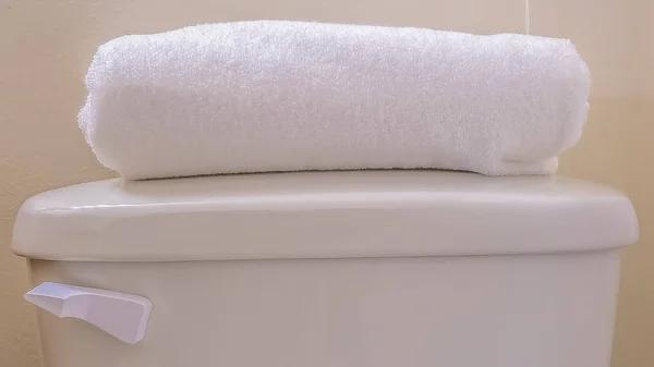 Panorama Tutup tangki toilet dengan handuk putih terlipat di atas tutup — Stok Foto