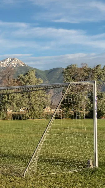 Marco vertical Red de fútbol en un campo de deportes con montaña cubierta de nieve y fondo cielo nublado —  Fotos de Stock