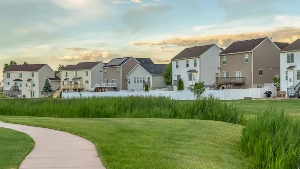 Marco panorámico Pasarela pavimentada en un terreno cubierto de hierba con casas y cielo nublado en el fondo — Foto de Stock