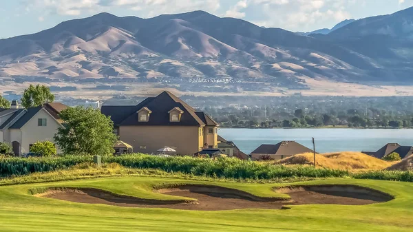 Панорама дома на фоне пруда для гольфа и озера с видом на возвышающиеся горы и долину — стоковое фото