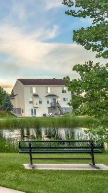 Dikey çerçeve Bench arka planda köprü ve aile evlerinin görünümü ile bir gölet bakan