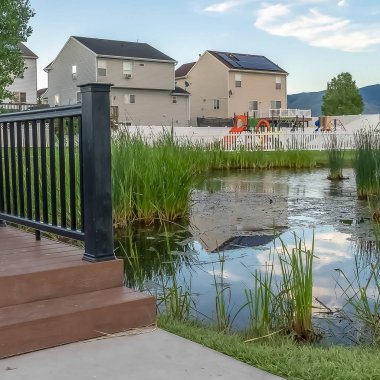 Evleri ve dağ arka plan ile bir mahalle parkı üzerinde bir gölet üzerinde Square Bridge