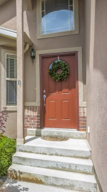 Çelenk ile süslenmiş kahverengi ön kapı ile bir evin girişinde Dikey çerçeve Merdivenler