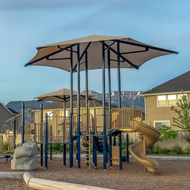 Bir çocuk oyun alanı etrafında banklar ve yol ile Square Neighborhood park