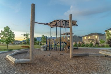 Dağ ve bulutlu mavi gökyüzü manzaralı bir mahallede oyun alanı ve evler