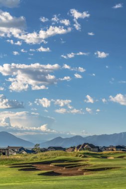 Güneşli bir günde mavi gökyüzü altında bir golf sahası ve yerleşim alanı manzara görünümü