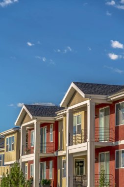 Güneşli bir günde gökyüzüne karşı kırmızı ve krem dış duvar kombinasyonu ile Homes