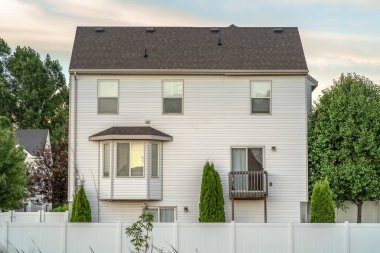 Beyaz duvar cumbalı pencere küçük balkon ve ahşap çit ile ev cephe