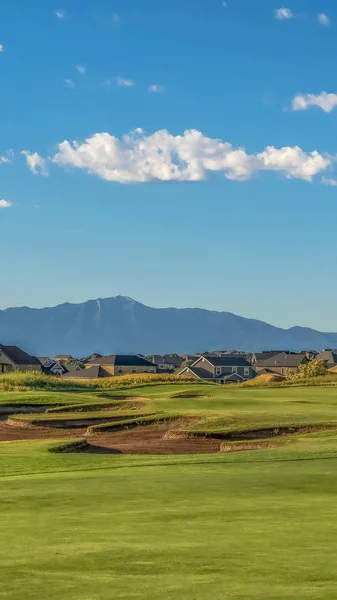 Moldura vertical Vista pitoresca de um campo de golfe com residências e montanha ao fundo — Fotografia de Stock