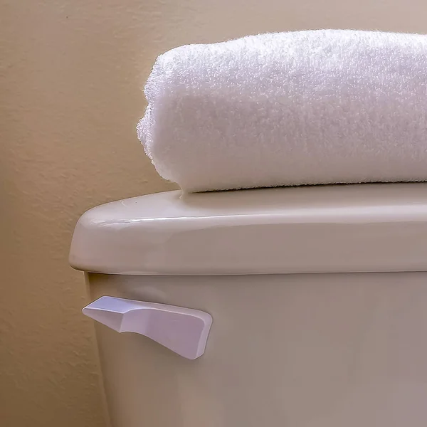 Vierkant close-up van de tank van een toilet met een gevouwen witte handdoek bovenop het deksel — Stockfoto