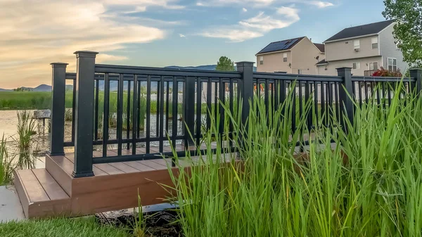 Panorama-Seitenansicht der Brücke über einen Teich in einem landschaftlich reizvollen Park mit Häusern im Hintergrund — Stockfoto