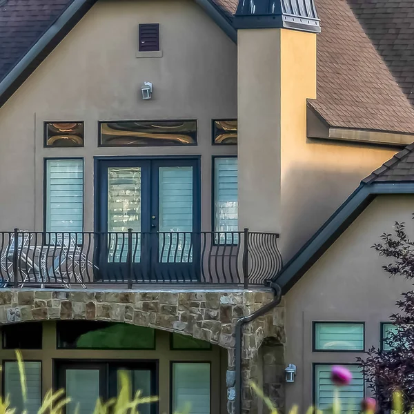 Marco cuadrado Hermosa casa con balcón vista detrás de hierbas verdes vibrantes en un día soleado — Foto de Stock