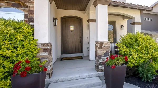 Panorama Home facade with arched entrance flanked by vibrant plants and colorful flowers — Stock Photo, Image