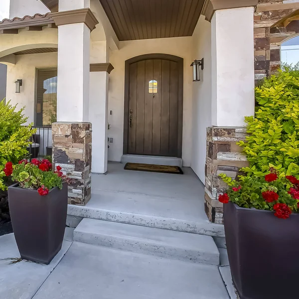 Square frame Home facade with arched entrance flanked by vibrant plants and colorful flowers — Stock Photo, Image