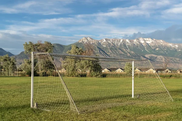 Red de fútbol en un campo de deportes con montaña cubierta de nieve y fondo cielo nublado —  Fotos de Stock