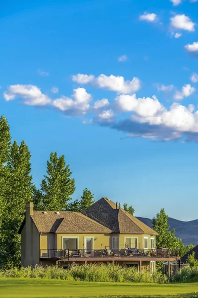 Árvores de casa e montanha em uma paisagem cênica sob o céu azul e nuvens inchadas — Fotografia de Stock