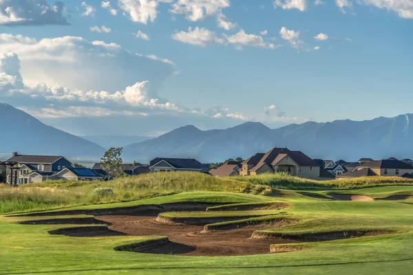 Golf course with houses and mountain in the background viewed on a sunny day — Stock Photo, Image