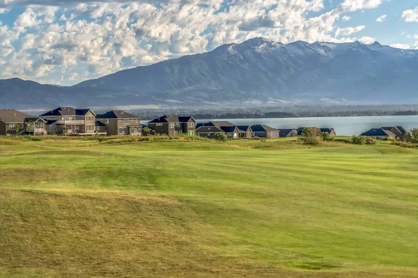 Zona residencial cerca de un lago con un extenso terreno herboso en primer plano — Foto de Stock