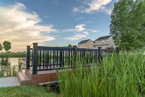 Seitenansicht der Brücke über einen Teich in einem landschaftlich reizvollen Park mit Häusern im Hintergrund — Stockfoto