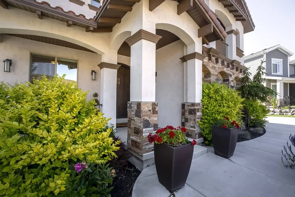 Home with an arched entrance and vibrant plants and flowers at the facade — Stock Photo, Image