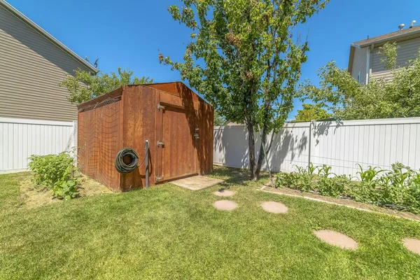 Small wooden shed at the garden of a home against blue sky on a sunny day