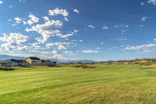 Fairway de um campo de golfe com vista para casas e montanha no fundo — Fotografia de Stock