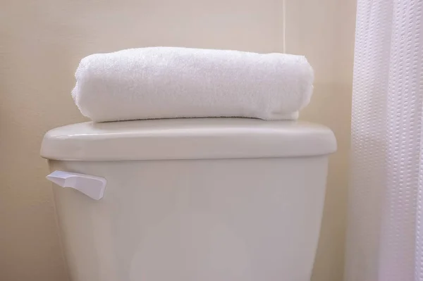 Close up of the tank of a toilet with a folded white towel on top of the lid — Stock Photo, Image