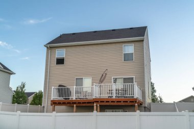 Beyaz yatay duvar kaplaması ve mavi gökyüzüne bakan balkonlu ev