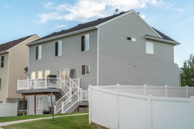 Gri yatay ahşap kaplamalı ve merdivenleri balkona çıkan bir ev.