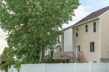 Beyaz duvarlı ve balkonlu bir evin bahçesindeki yemyeşil ağaç.