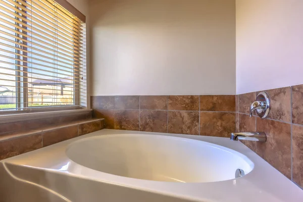 Oval küvete yakın bir banyo içinde fayanslı ve beton duvarlı.