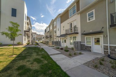 Güneşli bir günde parlak bulutların ve mavi gökyüzünün altında görünen konak evleri.