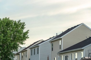 Gökyüzüne bakan evler ve yemyeşil ağaçlar bulutlarla kaplı.