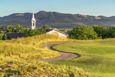 Çimenlerle kaplı bir yolda çan kulesi ve çatı arkaplanı vardı.