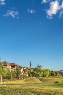 Mavi gökyüzü ve bulutların altında evleri ve dar yolları olan manzaralı bir yerleşim yeri.