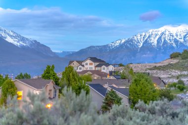 Karlı dağlarla kaplı muhteşem bir manzara ve mavi gökyüzüne ve bulutlara karşı evler.