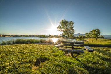 Piknik masası ve parlak güneş ve mavi gökyüzü manzaralı park.