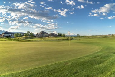 Golf sahası ve güneşli bir günde mavi gökyüzü ve kabarık bulutlar havai ile evler