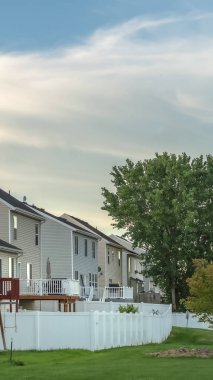 Çimenli bahçeli evler, balkonlu merdivenler ve beyaz çitler.