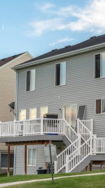 Gri yatay ahşap kaplamalı bir ev ve balkona çıkan merdivenler.