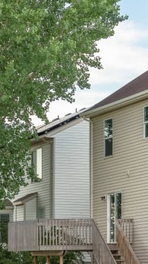 Beyaz duvarlı ve balkonlu bir evin bahçesindeki yemyeşil ağaç.