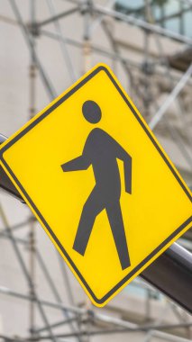 Vertical Close up view of a yellow and black diamond shaped Pedestrian Crossing sign clipart