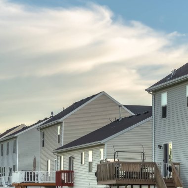 Çimenli bahçeli evler, balkonlu merdivenler ve beyaz çitler.