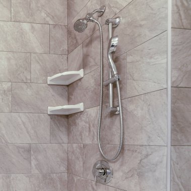 Kare küvet ve paslanmaz çelik duş gri ve beyaz fayans duvara karşı